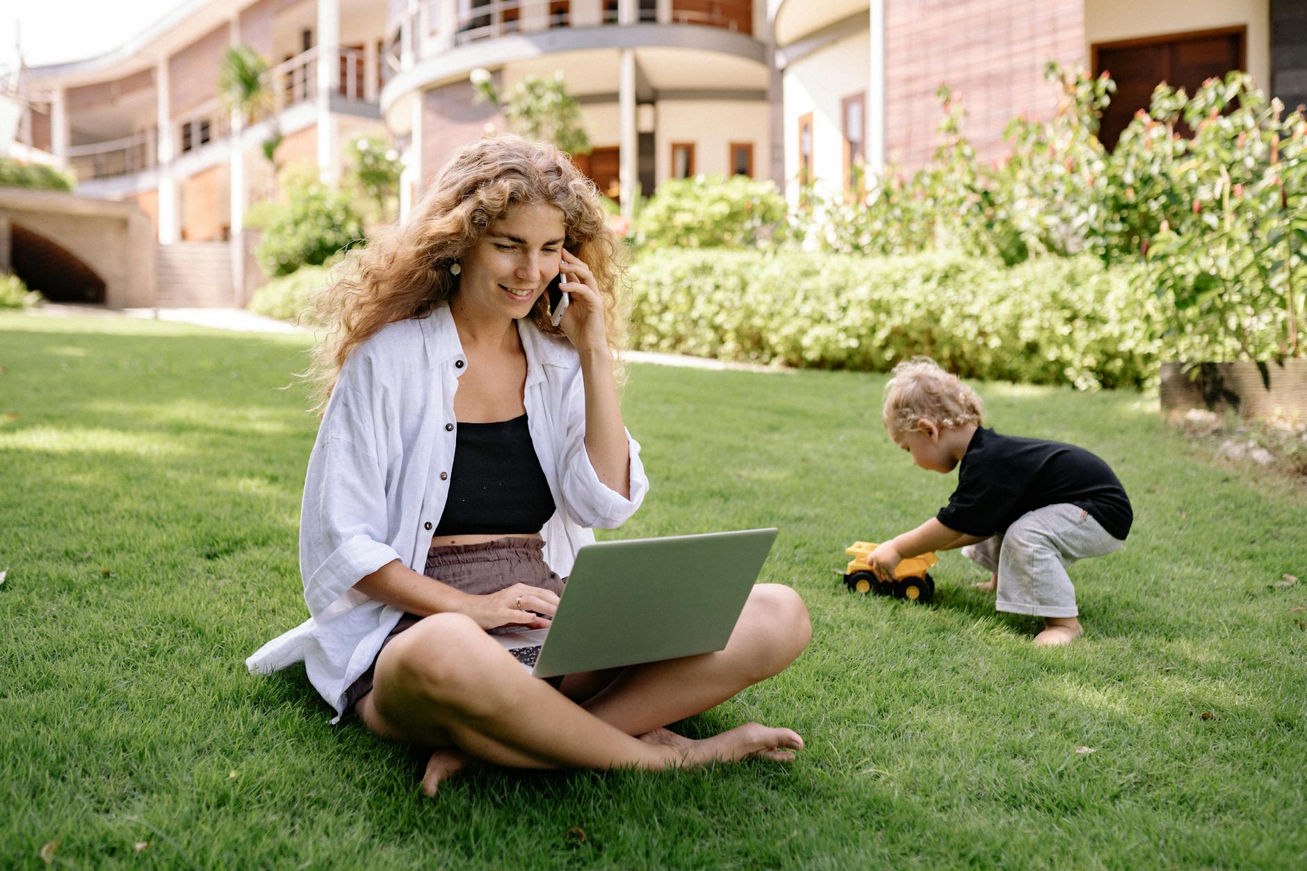 smiling blonde woman sitting with laptop in garden