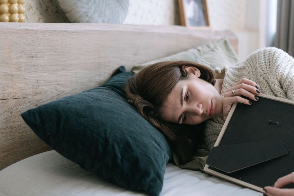 a woman hugging a picture frame while lying down on a bed